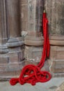 Red barrier rope with brass hook attached to wall in old building