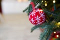 Red bauble hanging from a decorated Christmas tree, happy new year background with copy space Royalty Free Stock Photo