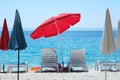 Red beach umbrella and chaise for relax and comfort on sea coast. Happy summer vacations and tourism concept. Paid service on