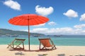 Red beach umbrella and deck chairs on the sand Royalty Free Stock Photo