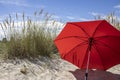 Red beach umbrella in the sand between dunes with blue summer sky Royalty Free Stock Photo