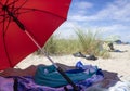 Red beach umbrella in the sand between dunes with blue summer sky Royalty Free Stock Photo