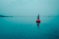 Red beacon floating in the sea with the sky and the horizon in the background