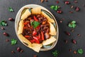 Red bean with nachos or pita chips, pepper and greens on plate over dark background Royalty Free Stock Photo
