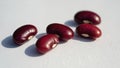 Red beans are placed on a white background, illuminated by bright light, creating clear shadows. The smooth texture and Royalty Free Stock Photo