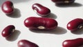 Red beans are placed on a white background, illuminated by bright light, creating clear shadows. The smooth texture and Royalty Free Stock Photo