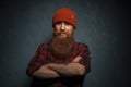 Red bearded man with orange hat and plaid shirt on cyan background