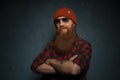 Red bearded man with orange hat and plaid shirt on dark cyan background