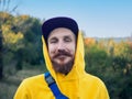 Red bearded millennial man with mustache in yellow hoody smiling portrait closeup Backpacker hiking climbing mountains Royalty Free Stock Photo