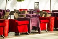 Red and beige armchairs are next to the restaurant tables, which are covered with long burgundy tablecloths