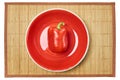 Red bell pepper on a red plate on a cane place mat