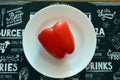 Red bell pepper on white food plate on black background. Healthy vegetarian organic dinner cooking