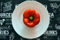 Red bell pepper on white food plate on black background. Healthy vegetarian organic dinner cooking