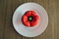 Red bell pepper on white food plate on wooden background. Healthy vegetarian organic dinner cooking