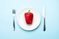 Red bell pepper on a white plate, fork and knife, dieting, healthy food concept. Fresh pepper, health. Food creative concept. Top Royalty Free Stock Photo