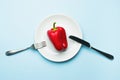 Red bell pepper on a white plate, fork and knife, dieting, healthy food concept. Fresh pepper, health. Food creative concept. Top Royalty Free Stock Photo