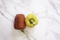 Red Bell and Yellow Bell Pepper on a White Marble Background