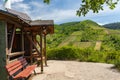 A red bench standing on the hill of the winery next to a wooden house, in the background beautiful vineyards in the spring. Royalty Free Stock Photo