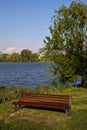Red bench with a tree by the shore of a lake in spring Royalty Free Stock Photo