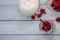 Red berries in a glass transparent bowl and sugar; currants in a jar on a light background Royalty Free Stock Photo