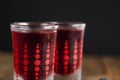 Red berries liqueur in shot glass isolated on black background and wooden table. Homemade alcohol drink concept. Royalty Free Stock Photo