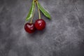 Red berries of ripe cherries with green leaves on a black craft background. Close-up photo of a berry.