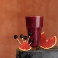 Red berry citrus smoothies cocktail. Dlass of drink and grapefruit or sicilian orange slices on blurred background. Soft