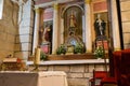 Red Bible and candle on altar table with saint sculptures and red chair. Faith and religion concept. Church interior with altar.