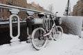 Red bicycle with baskets covered with snow leaning against a fence next to Griboedov Canal Royalty Free Stock Photo