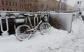 Red bicycle with baskets covered with snow leaning against a fence next to Griboedov Canal Royalty Free Stock Photo