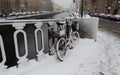 Red bicycle with baskets covered with snow leaning against a fence next to Griboedov Canal Royalty Free Stock Photo