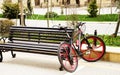 A red bicycle standing parked in a bike stand close to wooden bench. Street is made of blocks of granite Royalty Free Stock Photo