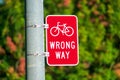 Red bicycle wrong way sign on street pole placed facing wrong-way bicycle traffic