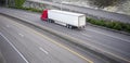 Red big rig long haul semi truck with dry van semi trailer running on divided wide highway