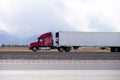 Red big rig semi truck carry refrigeration semi trailer and going by flat road in Utah Royalty Free Stock Photo