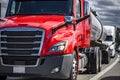 Red big rig semi truck with tank semi trailer running in convoy on the turning busy highway road Royalty Free Stock Photo