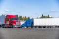 Red big rig semi truck with semi trailer running on the truck stop going to the exit driving past other trucks Royalty Free Stock Photo