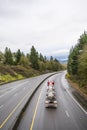 Red big rig semi truck transporting Chemical and flammable liquids in tank semi trailer running on the divided wet slippery road Royalty Free Stock Photo