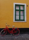 Red bike against a yellow wall, with green window, Copenhagen, Denmark Royalty Free Stock Photo