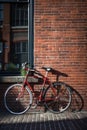 Red bike leaning against building brick wall in city street, created using generative ai technology Royalty Free Stock Photo