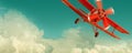 Red biplane flying in the cloudy sky. Retro style Royalty Free Stock Photo