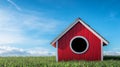 A red birdhouse on a grassy field under a blue sky. Royalty Free Stock Photo