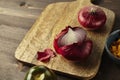 Red bisect onion, tomato, herbs and spice on wooden table.