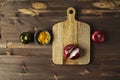 Red bisect onion, tomato, yellow spice on wooden table with cutting board.