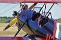 A Red and Black Airplane at a Flying Farmers show sitting by the runway by the airplane hanger on a colorful day.