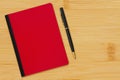 Red and black notebook with pen on a desk Royalty Free Stock Photo