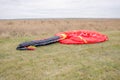 Red and black canopy paraglider lying on green grass against a cloudy sky background Royalty Free Stock Photo