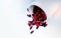 Red, black capsules pill spilled out from white plastic bottle container. Antibiotics drug resistance. Antimicrobial capsule pills Royalty Free Stock Photo