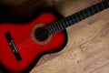 Red-black classical guitar standing on wooden floor Royalty Free Stock Photo