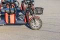Red-black family walking electric bikes with a basket on the handlebars, illuminated by the sun, stand on an asphalt
